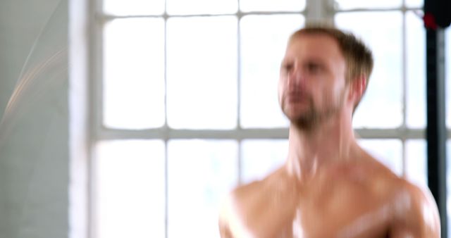 The image shows a shirtless man in motion while working out with a jump rope in a gym. The blur effect indicates high intensity and rapid movement. This can be used in fitness blogs, promotion of gym memberships, workout programs, or health and wellness articles.