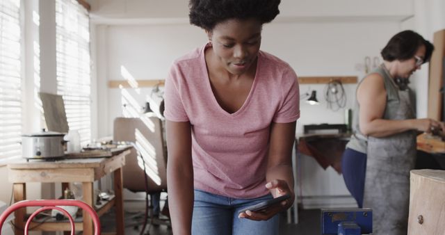 Young Woman Checking Phone While Working in Workshop - Download Free Stock Images Pikwizard.com