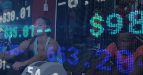 Rowing woman powering through intense gym cardio with digital financial ticker overlay