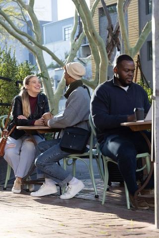 Couple laughing and holding hands at street-side cafe patio with laptop nearby