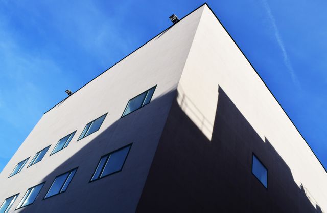 This simplistic photograph captures a modern, minimalist building with clean lines against a clear blue sky, perfect for use in urbanist design inspiration, real estate advertisements, or architectural portfolio showcases.