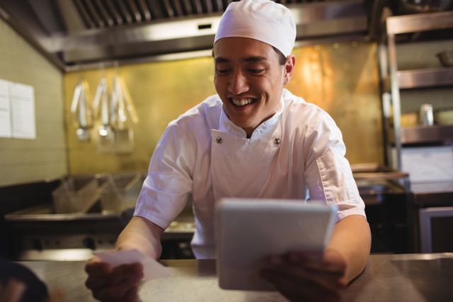Smiling chef looking at an order list in the commercial kitchen