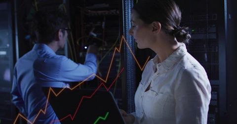 Female it engineer monitoring server metrics with laptop inside datacenter rack environment