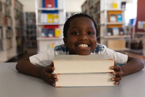 Joyful Young Student in Library With Books