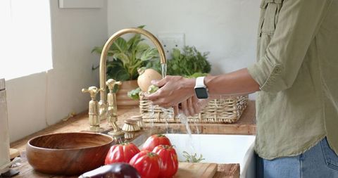 Woman Washing Fresh Greens in Rustic Home Kitchen