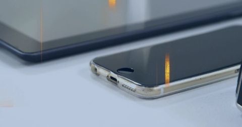 Minimal workspace with scuffed clear-cased smartphone resting near tablet on white surface