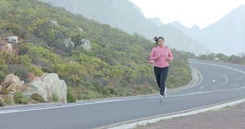 Woman Jogging on Scenic Mountain Road in Pink Sweatshirt