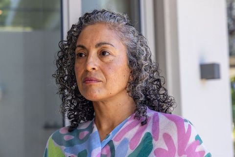 Reflective middle-aged african american woman standing at glass door wearing pastel shawl
