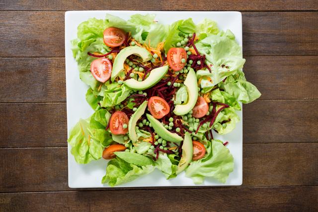 Plate of fresh salad on wooden board