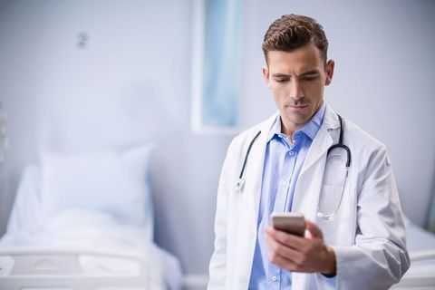 Doctor Using Smartphone in Hospital Room with Stethoscope