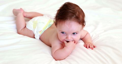 Adorable Baby in Diaper Nibbling Fingers on Bed - Download Free Stock Images Pikwizard.com