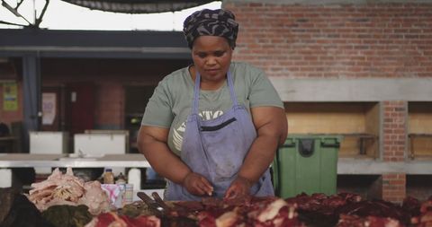 African female butcher skillfully preparing fresh meat in market
