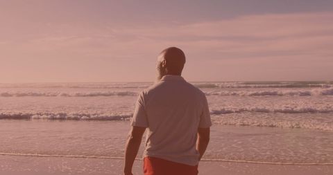 Senior Man Enjoying Quiet Beach Walk at Sunset