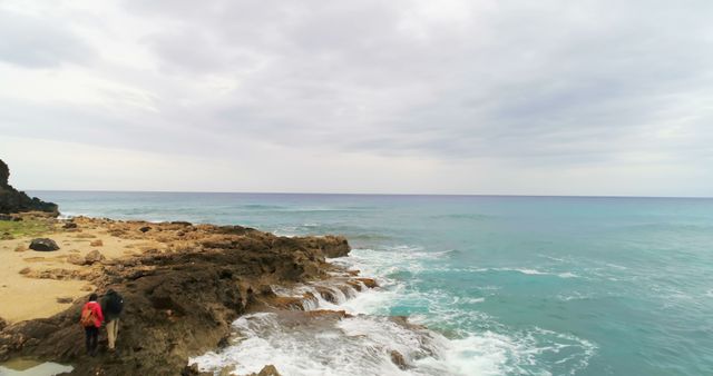 Couple Walking Along Rocky Coastline by the Ocean Under Overcast Sky - Download Free Stock Images Pikwizard.com