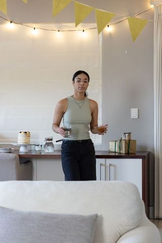 Woman Celebrating at Home with Cake and Lights