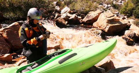 Woman preparing for kayaking adventure in river rapids