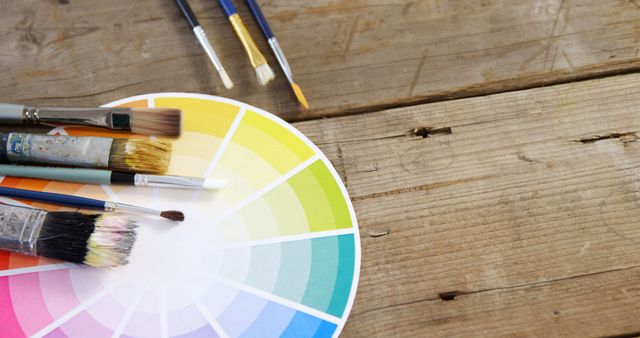 Paintbrushes with color swatch on wooden background
