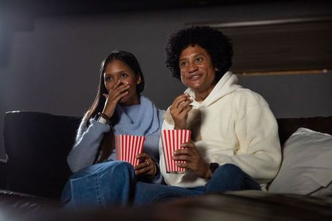 Diverse couple enjoying movie night with popcorn in cozy living room