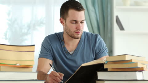 Focused Man Taking Notes From Books at Home