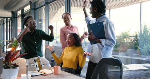 Joyful Team Celebrating Success with High-Fives in Modern Office Setting