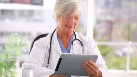 Smiling Senior Doctor Uses Tablet in Bright Office Setting
