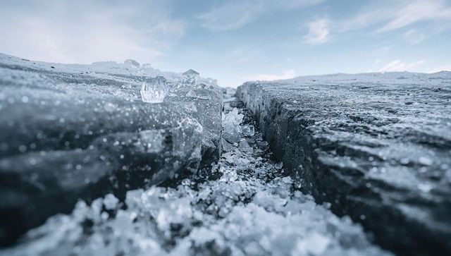 Crystalline crevasse cutting frozen glacier surface with low-angle clear ice crystals