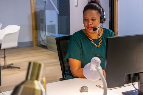 Customer support agent wearing headset working at modern office desk with computer