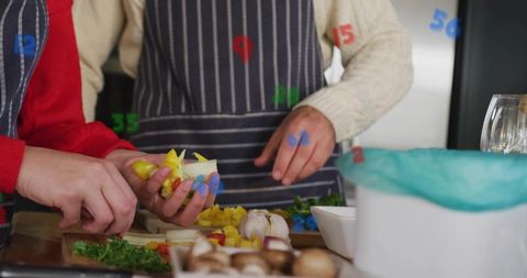 Couple chopping vegetables together wearing striped aprons for cozy home cooking