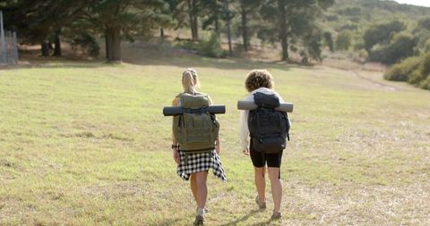 Adventure trekking: two women hiking towards forested trail