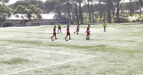 Youth soccer players and referee on sunny field