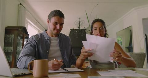 Couple planning wedding with laptop and documents at home