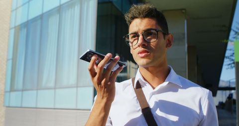 Young Man Speaking into Smartphone Outdoors in City Setting - Download Free Stock Images Pikwizard.com