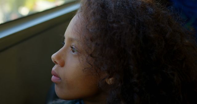 Pensive Young Girl Looking Through Window with Curly Hair in Natural Light - Download Free Stock Images Pikwizard.com