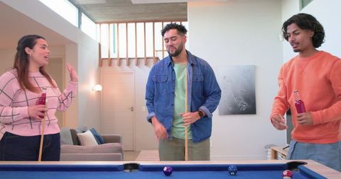 Diverse Friends Playing Pool in Modern Living Room with Blue Felt Table and Drinks