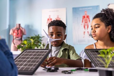 African american children assembling wind turbine and solar panels in stem classroom
