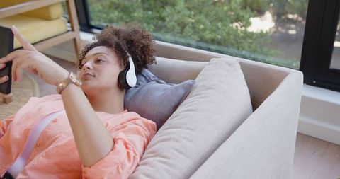 Woman Relaxing on Sofa with Smartphone in Modern Living Room