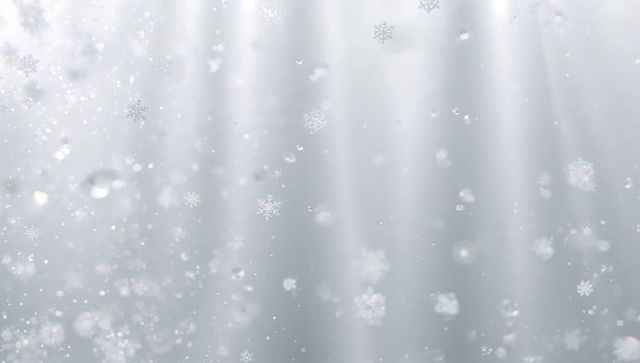 Falling snowflakes drifting through soft gray winter light shafts with bokeh sparkle