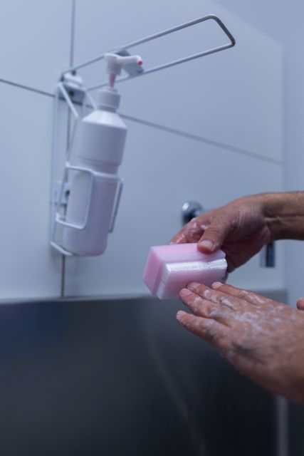 Close-up of male surgeon scrubbing hands with brush at sink in hospital