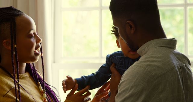 Young Family Interacting Playfully Near Sunlit Window - Download Free Stock Images Pikwizard.com