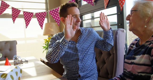 Young man celebrating special occasion with elderly woman at home - Download Free Stock Images Pikwizard.com