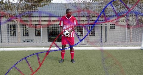 Standing soccer goalkeeper holding ball on turf with DNA helix overlay for sports genetics