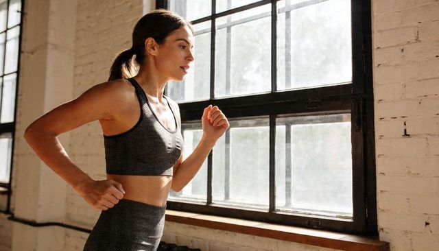 Female runner jogging beside industrial window in minimalist loft fitness studio