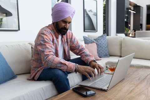 Man with turban typing on laptop in stylish home office