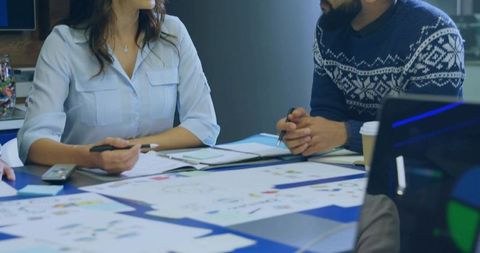 Colleagues Collaborating at Conference Table with Charts and Laptop