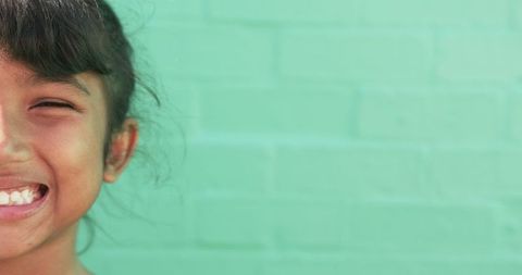 Smiling Young Student Against Vibrant Green Brick Background
