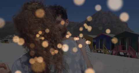 Romantic Embrace with Bokeh and Beach Cabins