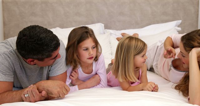 Parents Spending Quality Time with Their Two Daughters on Bed - Download Free Stock Images Pikwizard.com