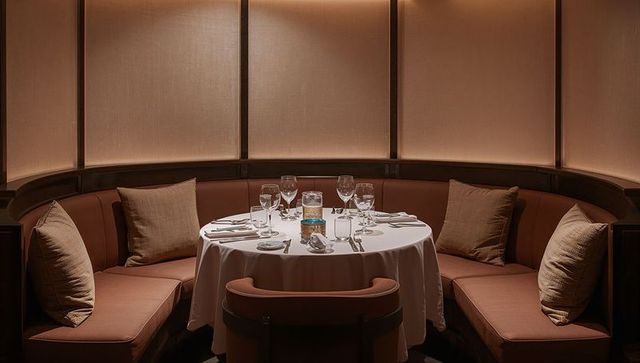 Intimate round booth dining with white tablecloth, candlelight and plush banquette