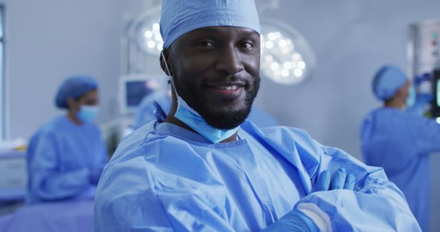 Portrait of african american male surgeon standing in operating theatre smiling to camera. medicine, health and healthcare services.