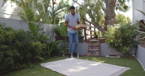 Man Arranging Wooden Steps in Lush Tropical Garden